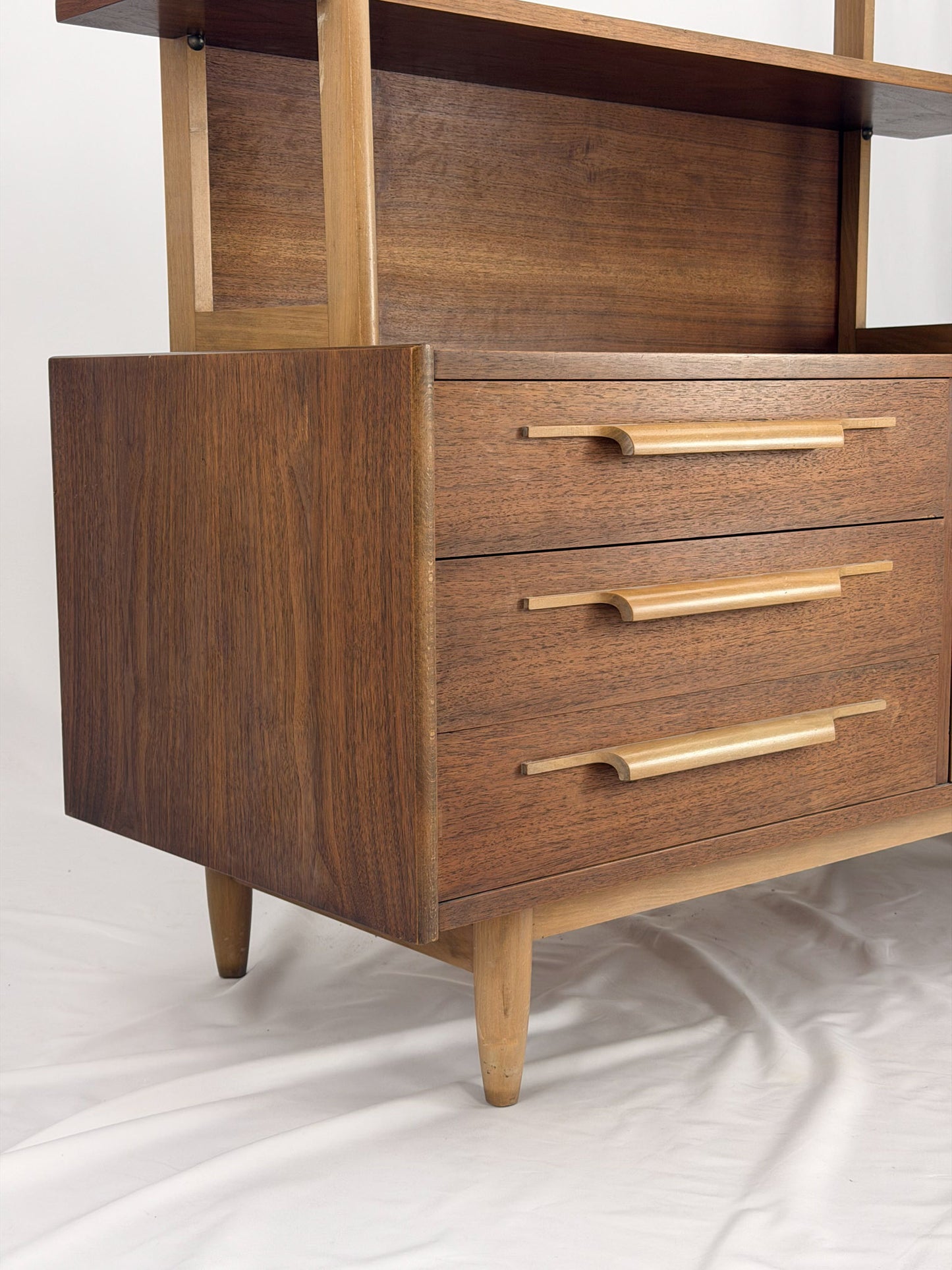 Wooden shelf unit with multiple shelves and drawers on a white background