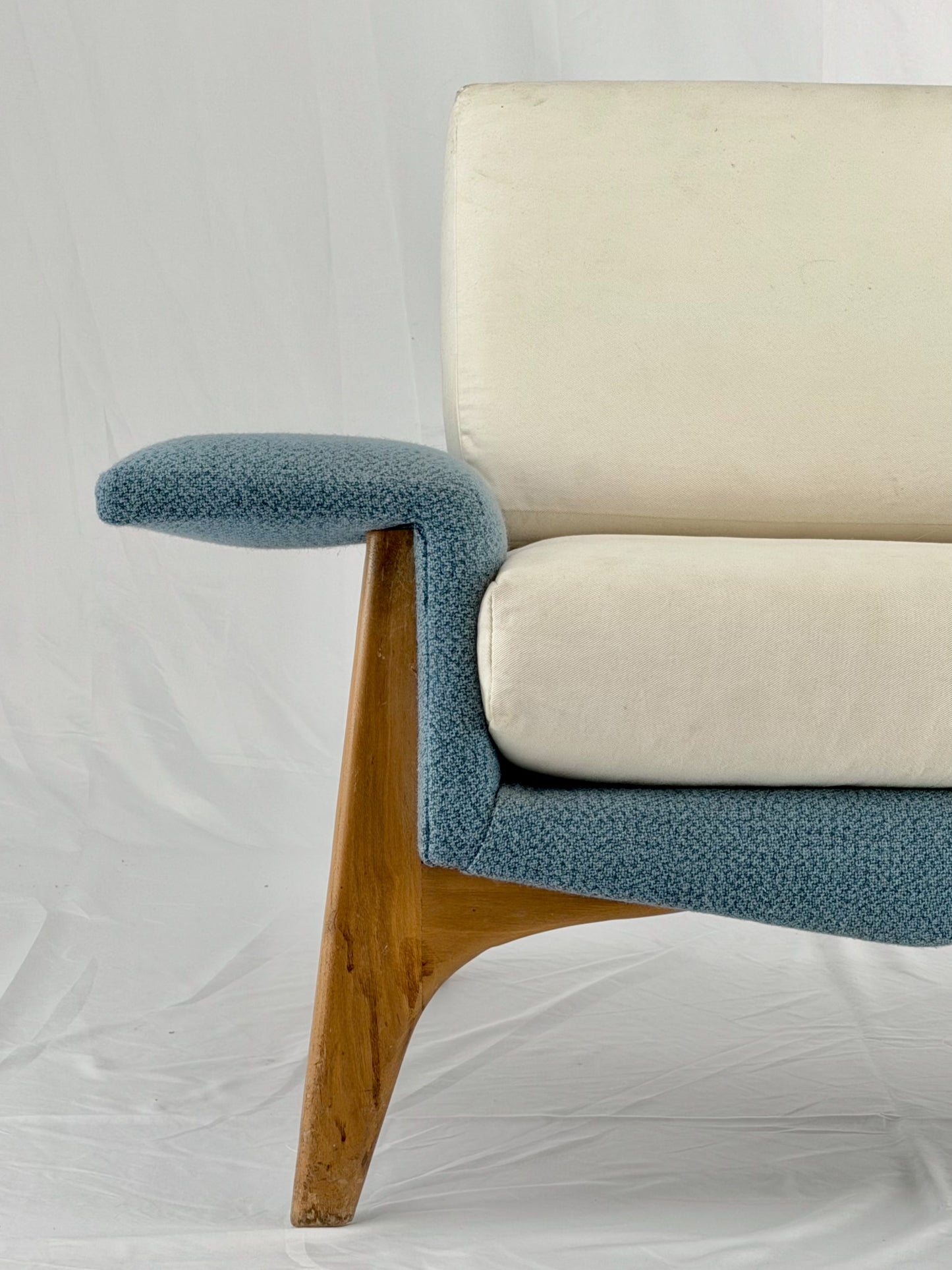 Armchair with blue cushions and wooden legs on a white background