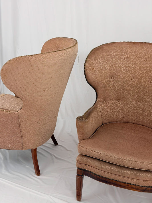 Two wingback chairs with blush colored upholstery on a white background
