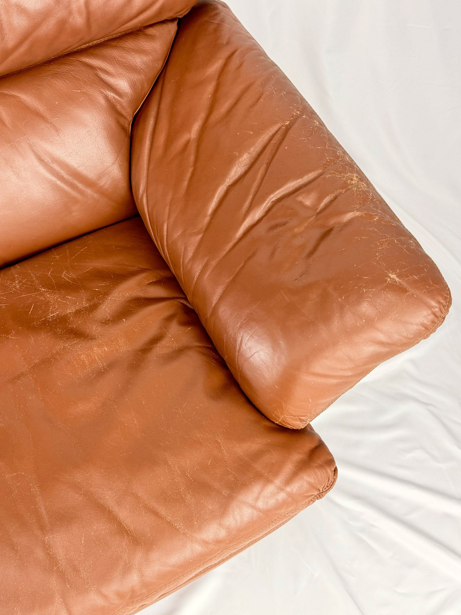 Brown leather sofa with visible wear on a white background
