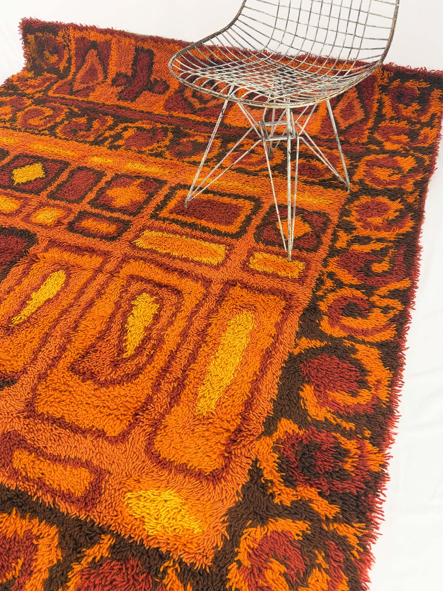 Rya shag rug with warm toned geometric pattern on a white background