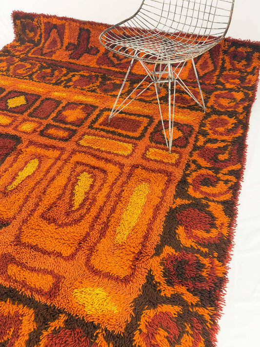 Rya shag rug with warm toned geometric pattern on a white background