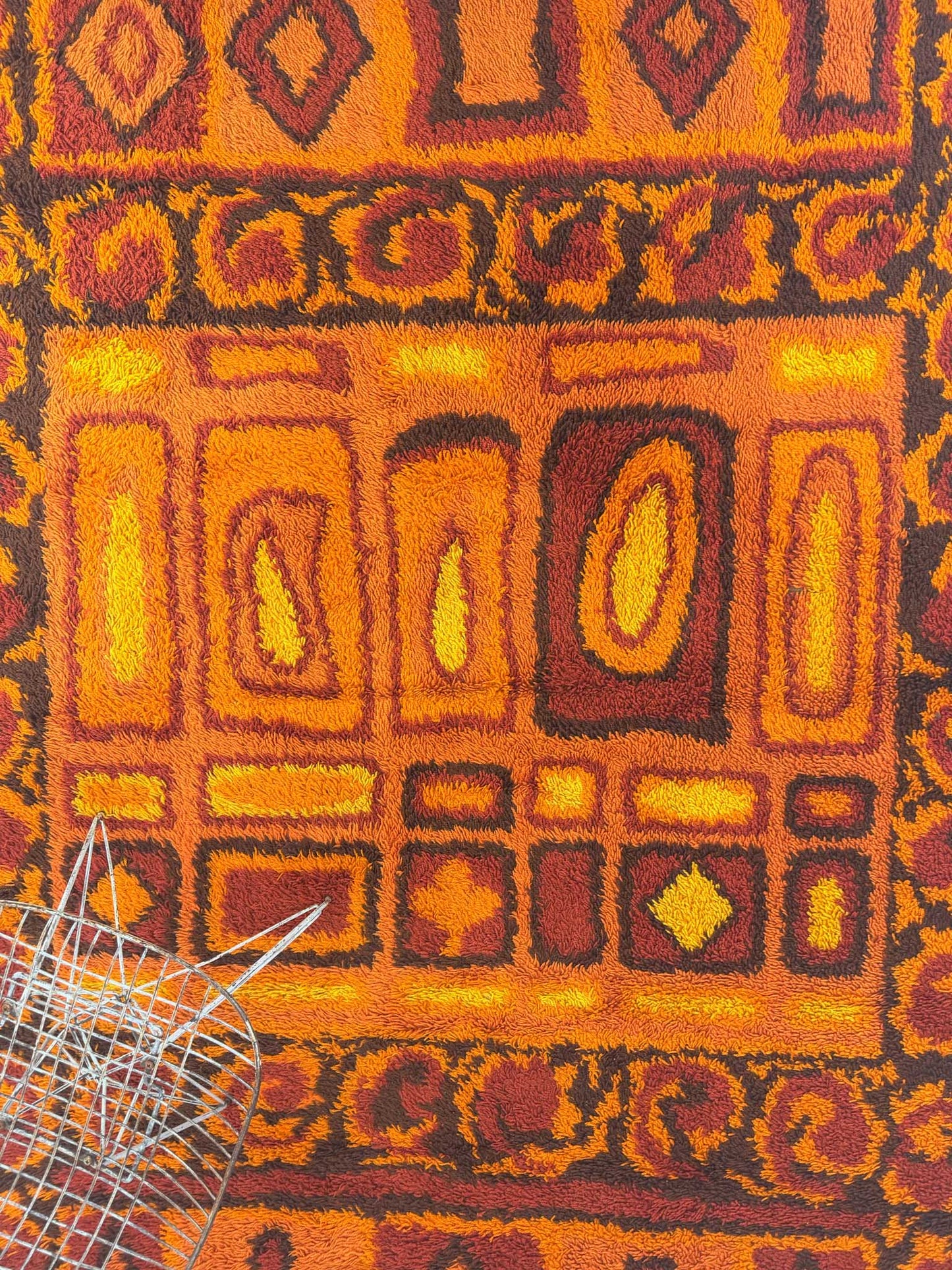 Close up of a Rya shag rug with warm toned geometric pattern on a white background
