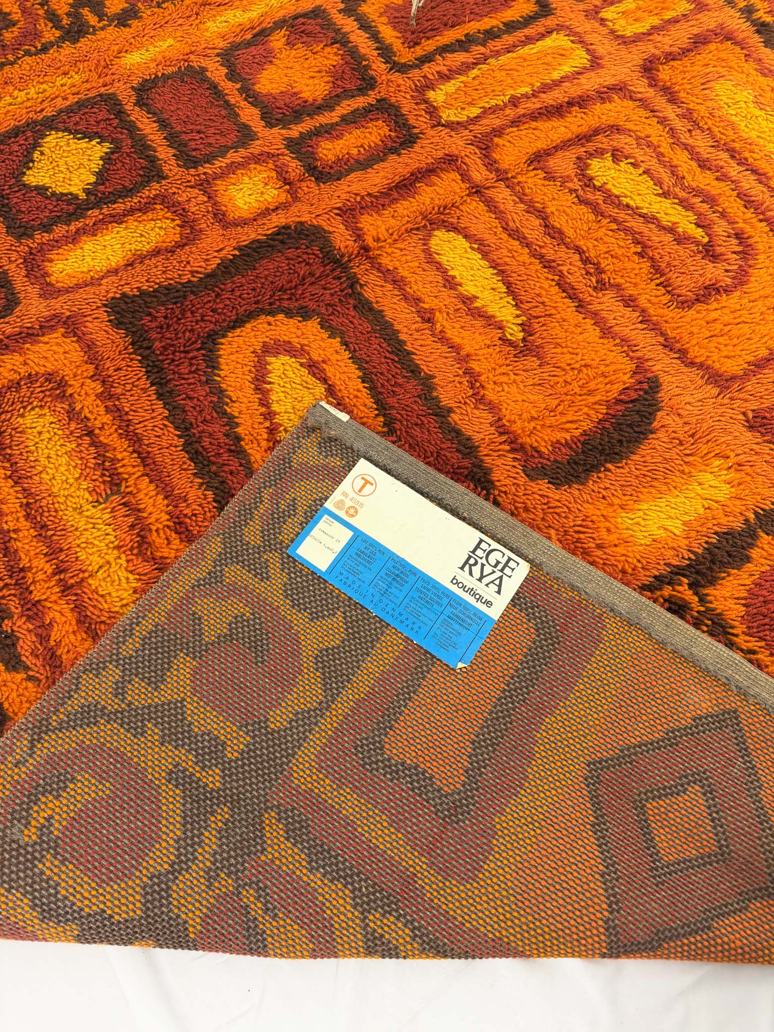 Close-up of a patterned rug with a brand label on a white background