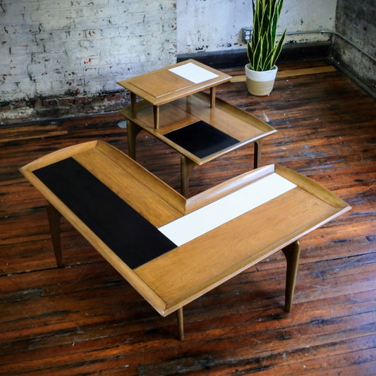 Wooden side table and boomerang coffee table with tile top on a wooden floor with a plant in the background.
