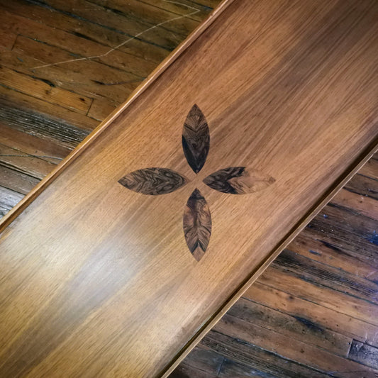 Wooden coffee table with leaf design on a rustic wooden floor.