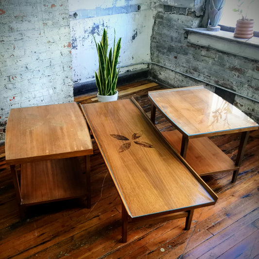 Three wooden tables on a wooden floor with a plant in the background.