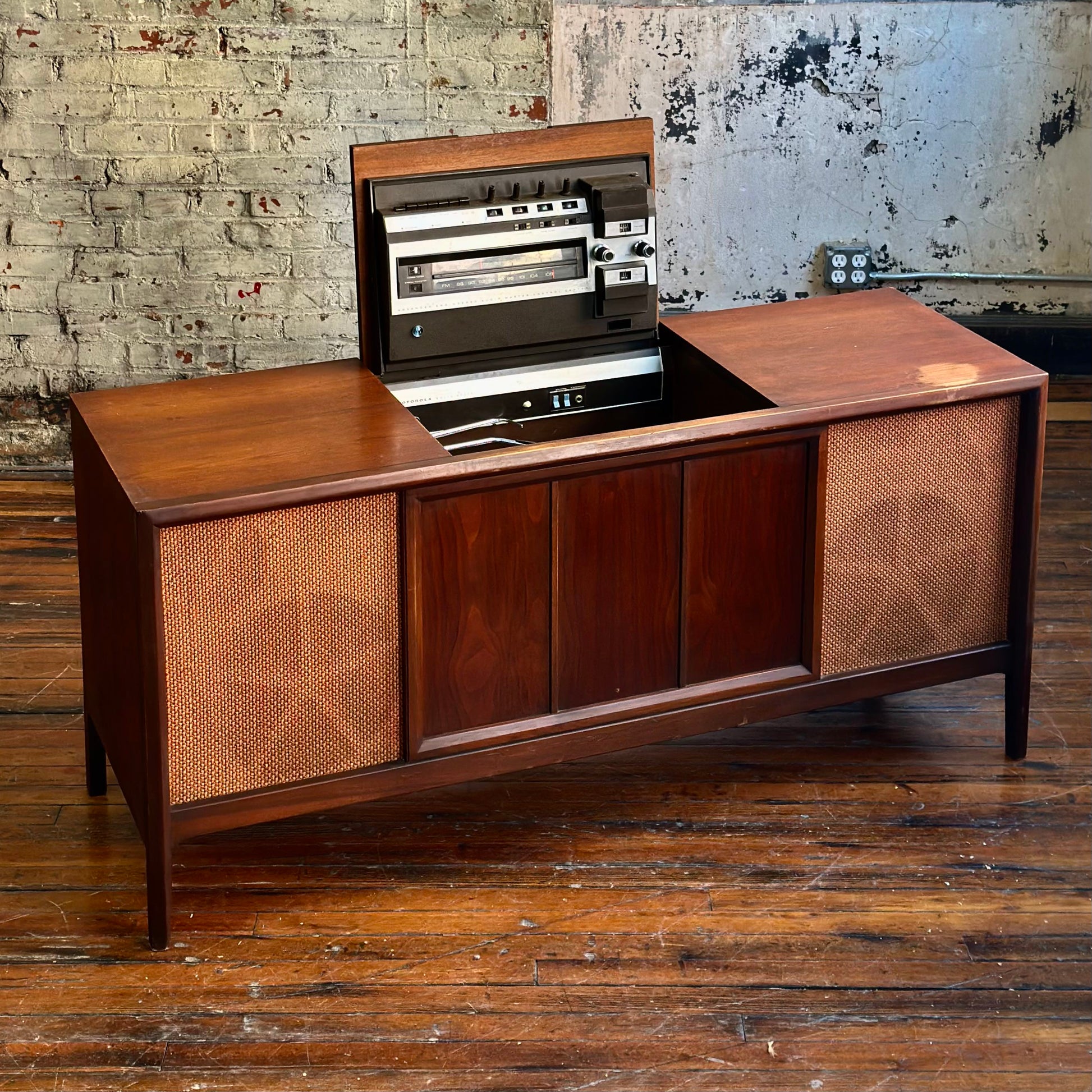 Wooden audio console with vintage design against a textured wall.