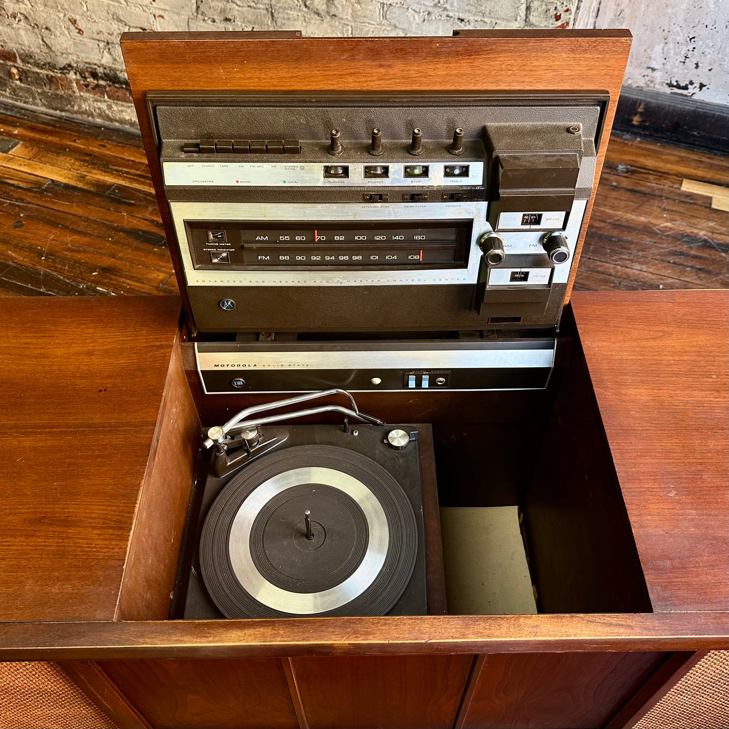 Vintage stereo console with turntable on a wooden surface.