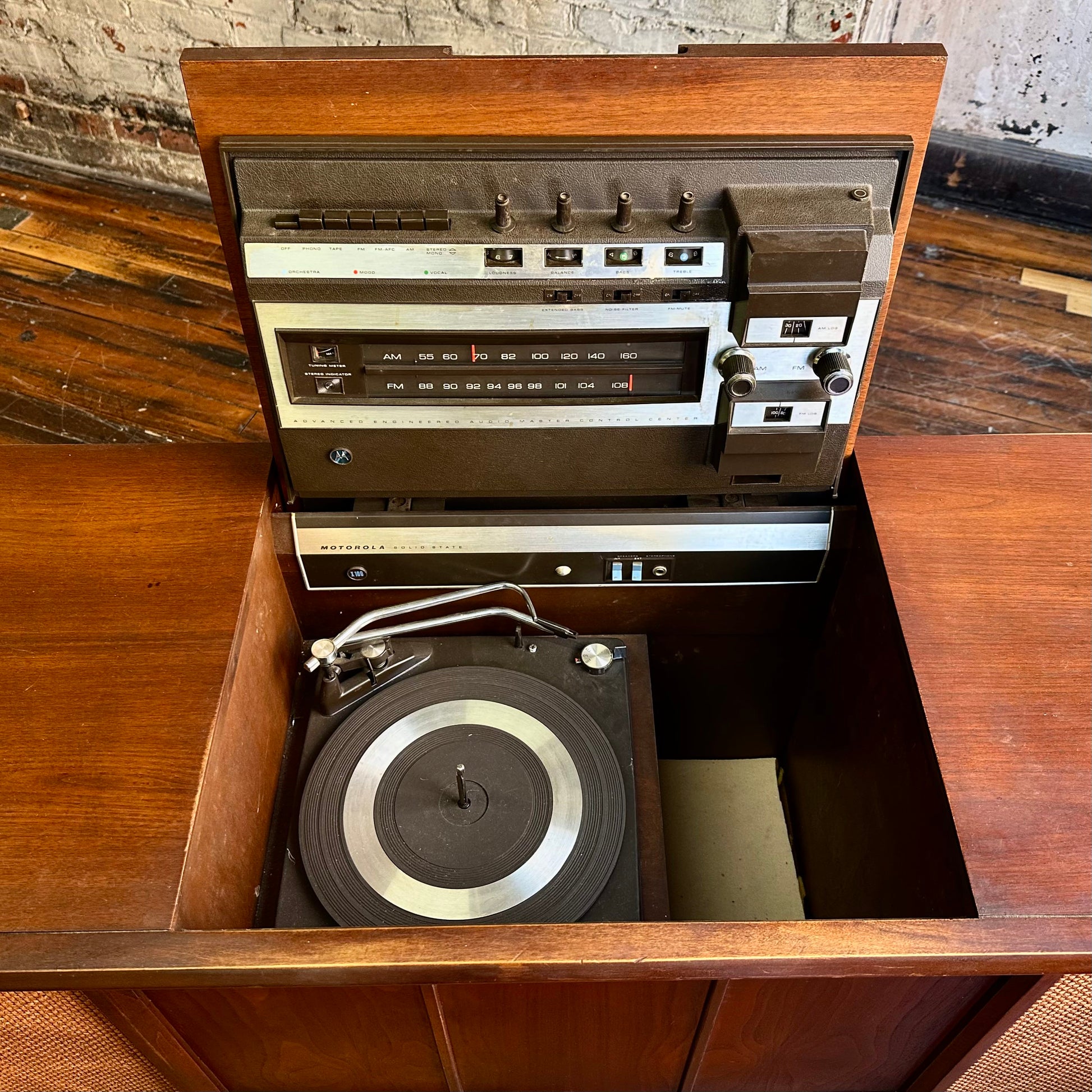 Vintage stereo console with turntable on a wooden surface.