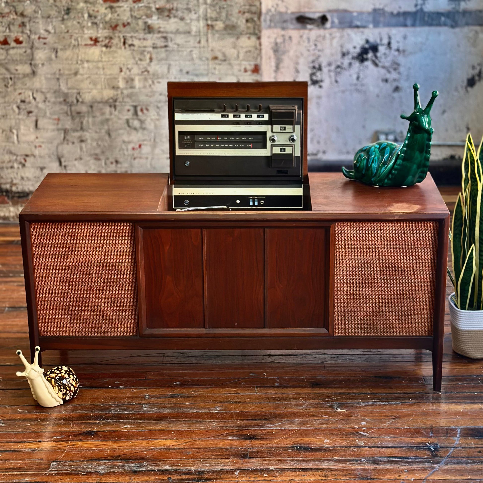 Wooden audio console with vintage design against a textured wall.