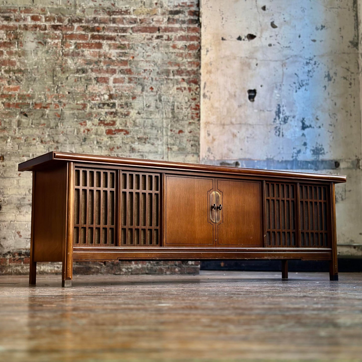 Wooden console with vintage radio against a rustic brick wall.