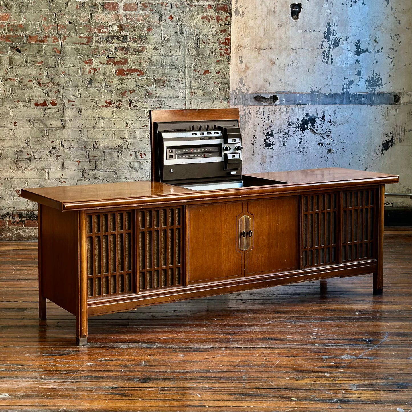 Wooden console with vintage radio against a rustic brick wall.