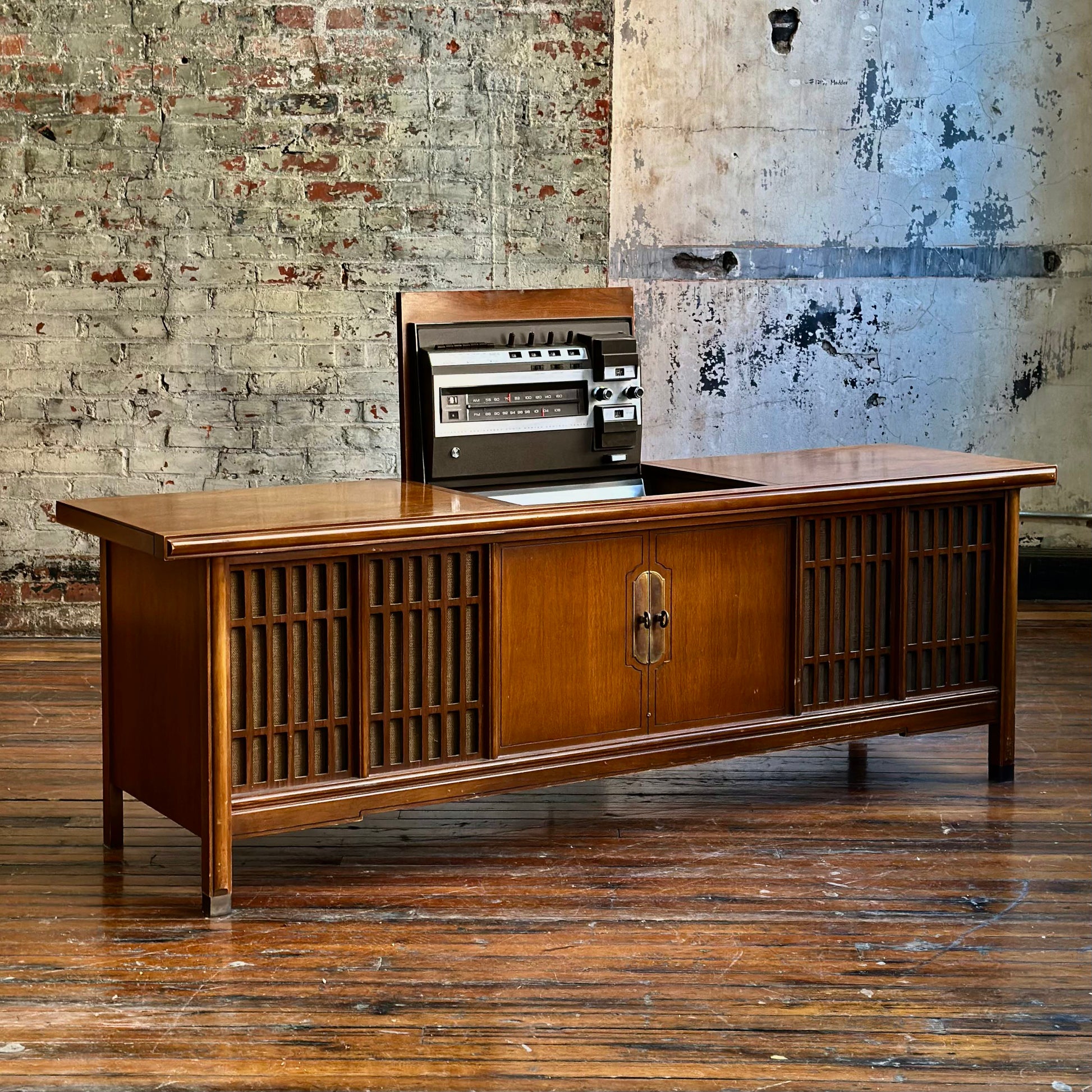 Wooden console with vintage radio against a rustic brick wall.