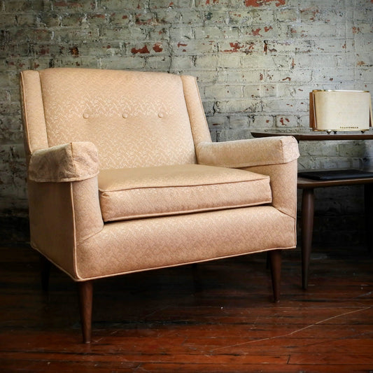 Beige armchair in a room with a brick wall and wooden floor.